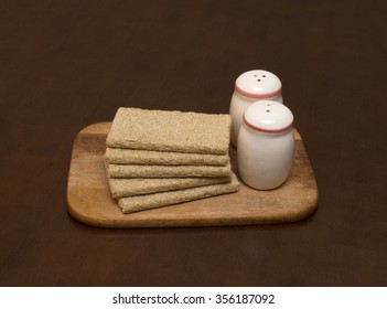 Small loafs and two saltcellars on a wooden chopping board  