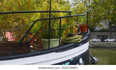 Small local garden at the front of a barge restaurant bar, on the Seine, maritime dwelling, in an urban environment, beautiful plant plantations in wooden pots or buckets, with large ropes - Powered by Shutterstock