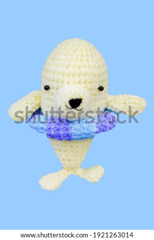Small lovely white dophin toy in crochet handmade on blue background and clipping path .