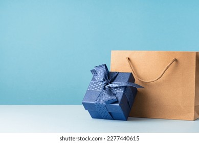 small Luxury gift box with a blue bow paper bag and agenda. Side view. Fathers day or Valentines day gift for him. Corporate gift concept or birthday party. Festive sale copy space - Powered by Shutterstock