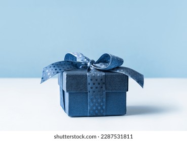 small Luxury gift box with a blue bow on light blue. Polka dot ribbon. Side view monochrome . Fathers day or Valentines day gift. Corporate gift concept or birthday party. Festive sale copy space - Powered by Shutterstock