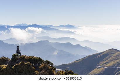 a small man hiking on the ling lines look at the distance in front of mountains background under big blue sky in Taiwan.