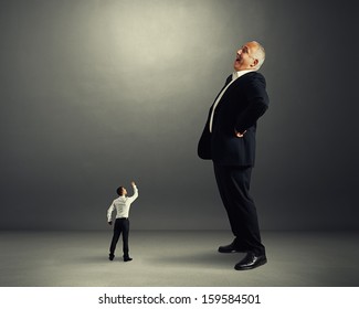 Small Man Showing Fist To Big Laughing Businessman