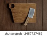 A small meat cleaver knife on wooden cutting board with holes