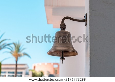 Small metal bell on the outside of a building.