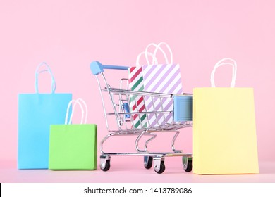 Small metal cart with shopping bags on pink background - Powered by Shutterstock