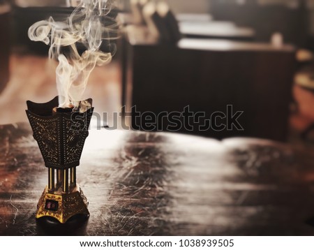 Small metal decorative Arabian Bakhoor incense burner censer with smoke and blurred background.