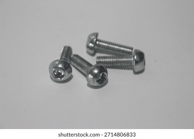 Small metal hex socket screws isolated on white background. Stainless steel machine screws for mechanical, industrial, and bicycle components, photographed in a clean studio setup.