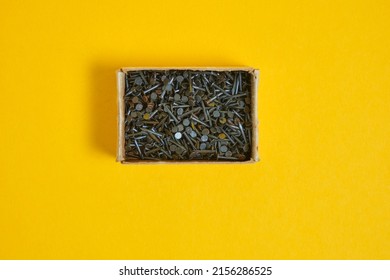 small metal nails for shoes and furniture in a box on a yellow background close-up