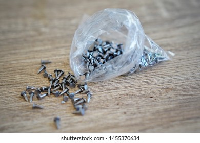 Small Metal Nails Spilled Out Of Plastic Bag On Wooden Backgrounds, Tools Construction Equipment Concepts