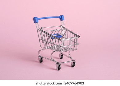 Small metal shopping cart on pink background - Powered by Shutterstock