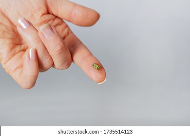 Small Microchip On A Person’s Finger.Conspirology. Population CONTROL. Power Over PEOPLE.People Management. Nanotechnology.Future Technologies In Microbiology Close-up, On A Gray Background, Copyspace