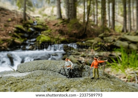 small miniature figures on a rock with a brook in the nature