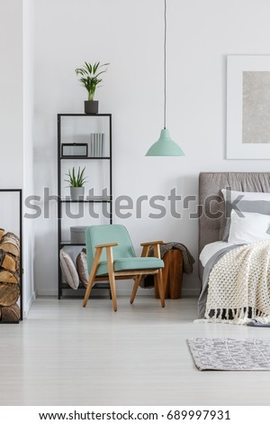 Small mint lampshade hanging above comfy wooden chair in bedroom