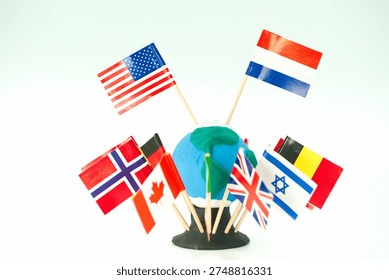 A small model of the Earth is shown with multiple flags of different countries positioned around it. The flags represent various nations and are attached with small sticks.