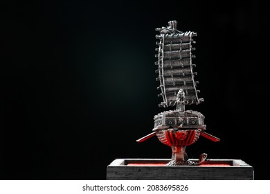 A Small Model Of Famous Ancient Korean Ironclad War Ship. Korean Turtle Ship On A Black Background. Black And White And Red.