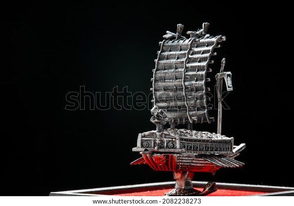 A small model of famous ancient Korean ironclad war\
ship. Korean turtle ship on a black background. Black and white and\
red.