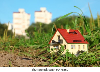 Small Model Of House In Focus. Two Big Houses In Out Of Focus.