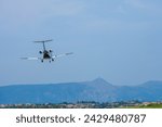 Small modern white business jet  landing at Corfu Ioannis Kapodistrias international airport. Mountain with trees and houses at the background.