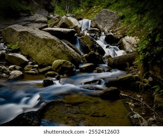 A small mountain stream gently flowing over large boulders, captured with a slow shutter speed to create a silky, smooth water effect. - Powered by Shutterstock