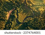Small narrow winding river, green fields and forest aerial view. Green beautiful rural drone landscape in sunset light. Nature, sustainable and ecology concept. Top down view. Beautiful nature texture