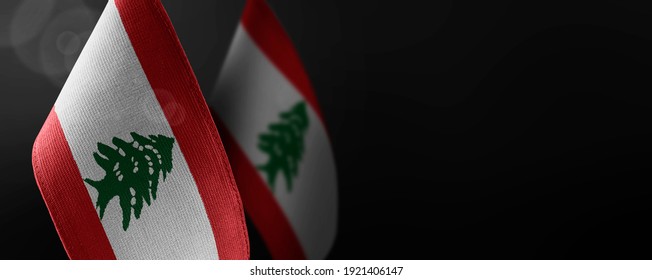 Small national flags of the Lebanon on a dark background