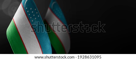Small national flags of the Uzbekistan on a dark background
