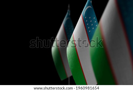 Small national flags of the Uzbekistan on a black background
