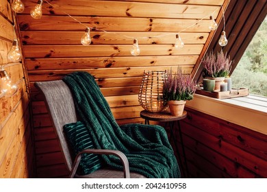 Small natural color wooden cabin balcony with heather flowers, candlelight flame, soft dark green plaid waiting on garden furniture chair. Cute autumn hygge home decor arrangement. - Powered by Shutterstock