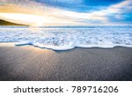 Small ocean sea waves on sandy beach with sunrise sunset. Background landscape picture of dusk or dawn at the Atlantic ocean beach with small waves at low tide. Background wallpaper picture.