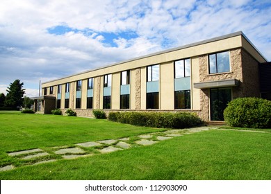 Small office or business building or college school perspective shot with sky and grass.