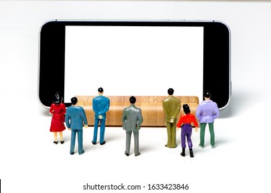 Small office people figures standing and watching a blank screen of a huge phone in front of them. White background. Copy space - Shutterstock ID 1633423846