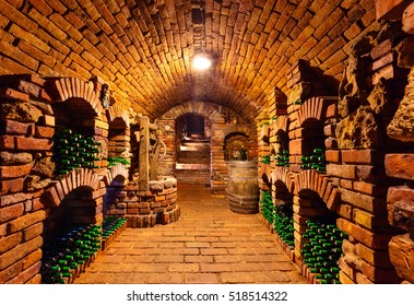 Small and old wine cellar with many full bottles and keg