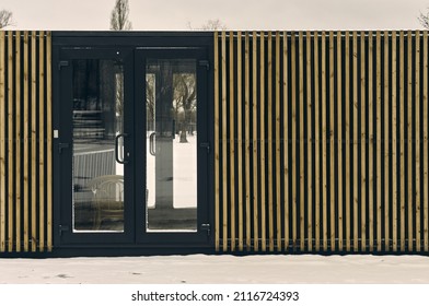 A Small One-story Building (warehouse) For Storing Inventory, The Walls Are Upholstered With Wooden Planks, Plastic Doors With Large Glass, No One Is There, Winter Mood