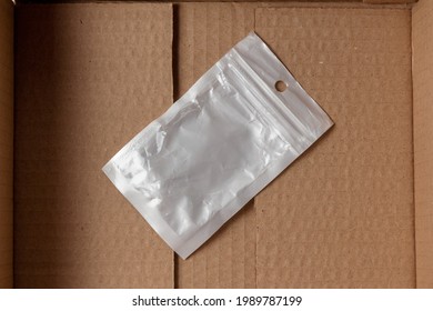 Small Opaque Silver Plastic Zip Lock Bag At The Bottom Of The Cardboard Box