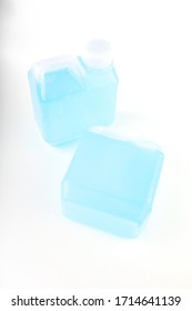 Small, Opaque White Gallon With Handle. Inside Is An Blue Alcohol Gel For Hand Washing And Sanitizing. On White Background.