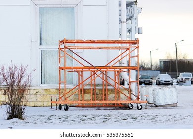 Small Orange Building Mobile Work Scaffolding Near A Large Sports Complex