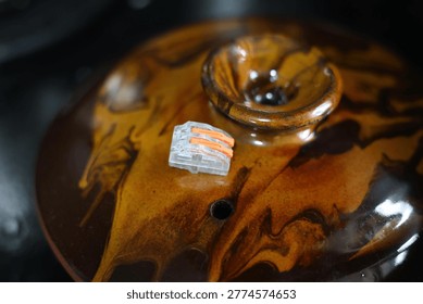 Small orange and clear electrical wire connector on textured surface