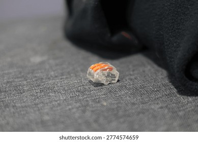 Small orange and clear electrical wire connector on textured surface