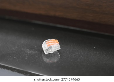 Small orange and clear electrical wire connector on textured surface