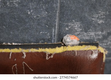 Small orange and clear electrical wire connector on textured surface