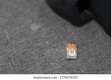 Small orange and clear electrical wire connector on textured surface