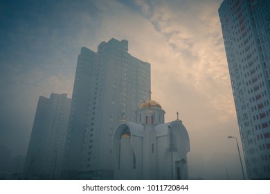 Small orthodox church at modern city residential district among high multi-storey buildings. Frosty foggy morning at city street. Kiev. Ukraine. - Powered by Shutterstock