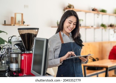 Small owned coffee shop Asian woman stand by using a tablet business and technology in the field of service.