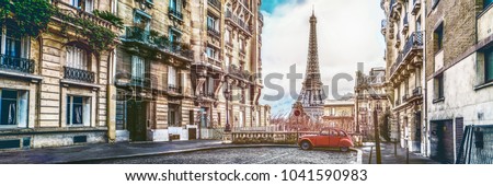 small paris street with view on the famous paris eiffel tower on a cloudy rainy day with some sunshine - wide horizontal panorama