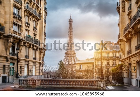 small paris street with view on the famous paris eiffel tower on a cloudy rainy day with some sunshine