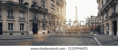 small paris street with view on the famous eiffel tower on a cloudy rainy day with some sunshine