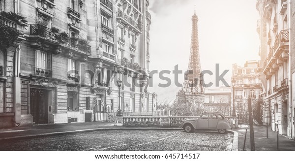 small paris street with view\
on the famous paris eifel tower on a cloudy rainy day with some\
sunshine