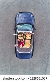 Small passenger sports convertible car with soft top down and happy family of young people enjoying lifestyle and freedom in aerial top down view.