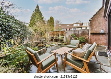 Small Patio With Gray Armchairs And Wooden Table With Green Hedge